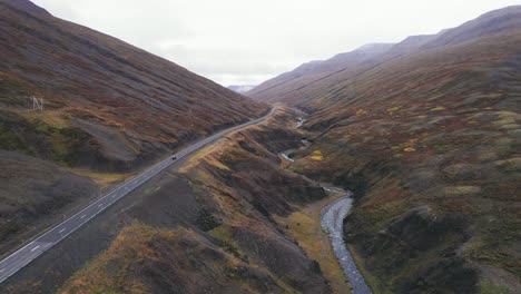 aerial: reverse reveal of black suv traveling along the iceland ring road which is a scenic highway through a picturesque remote fjord area leading to fog and haze in the distance