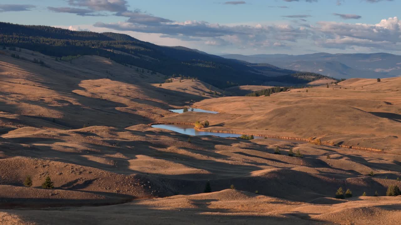 Aerial Symphony at Dusk: Grassland, Lake, and Forested Hills in Sunset's Glow