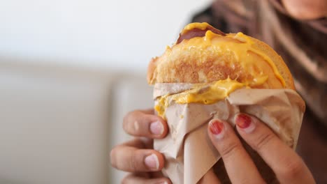 woman holding a cheese sandwich in paper bag