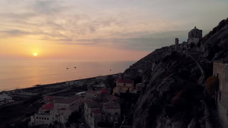 drone footage of a small italian town by the sea at sunset