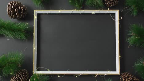 Video-of-christmas-decorations-with-string-lights-around-frame-and-copy-space-on-black-background