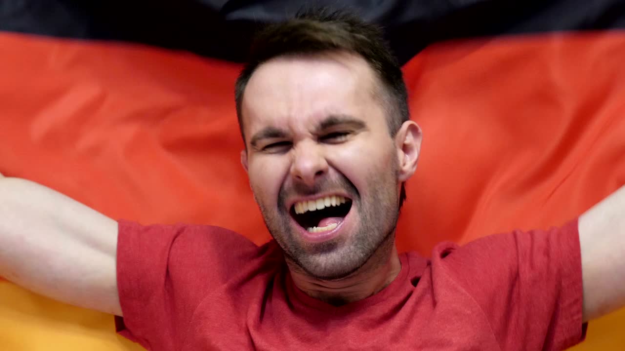 un aficionado alemán celebra sosteniendo la bandera de alemania en cámara lenta,4k, de alta calidad