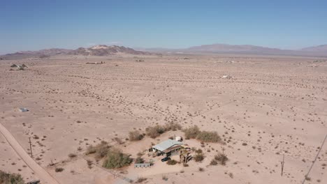 aerial shot panning above a lone house in the middle of a barren desert in california