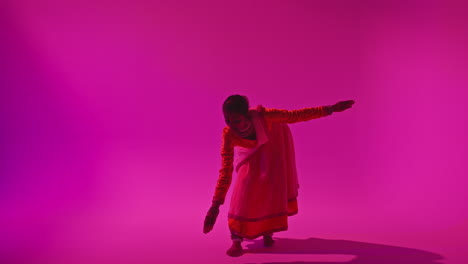 Full-Length-Studio-Shot-Of-Female-Kathak-Dancer-Performing-Dance-Wearing-Traditional-Indian-Dress-Against-Purple-Background-2