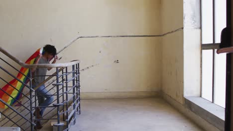 hombre afroamericano subiendo escaleras mientras sostiene una bandera lgbt