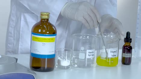 a scientist mixes vitamin c and starch solutions, observing changes in a laboratory setting.
