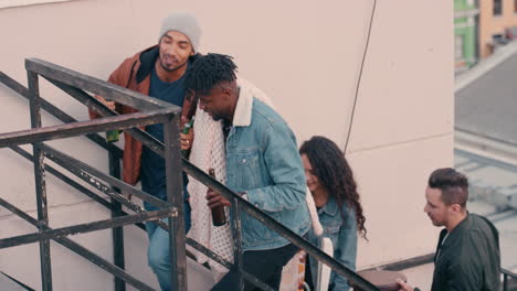 group of friends walking up fire escape stairs to rooftop party chatting sharing excitement preparing for weekend celebration in city