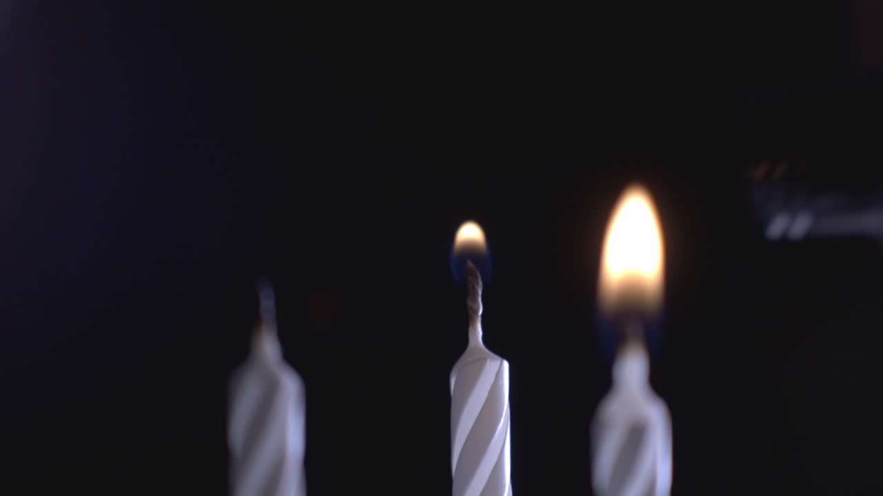 Tre candele accese con un accendino su sfondo nero. - primo piano