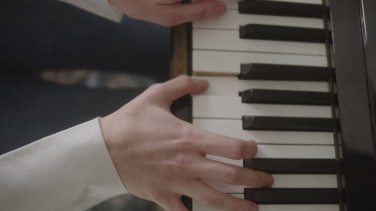 Beautiful slow motion, close-up shot of the hands and fingers of a beautiful young elegant woman as she plays classical and jazz piano music in the natural light of her home.