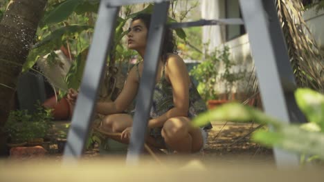 relax-woman-watering-the-beautiful-garden-from-behind-a-ladder-to-water-her-garden-with-sunbeam