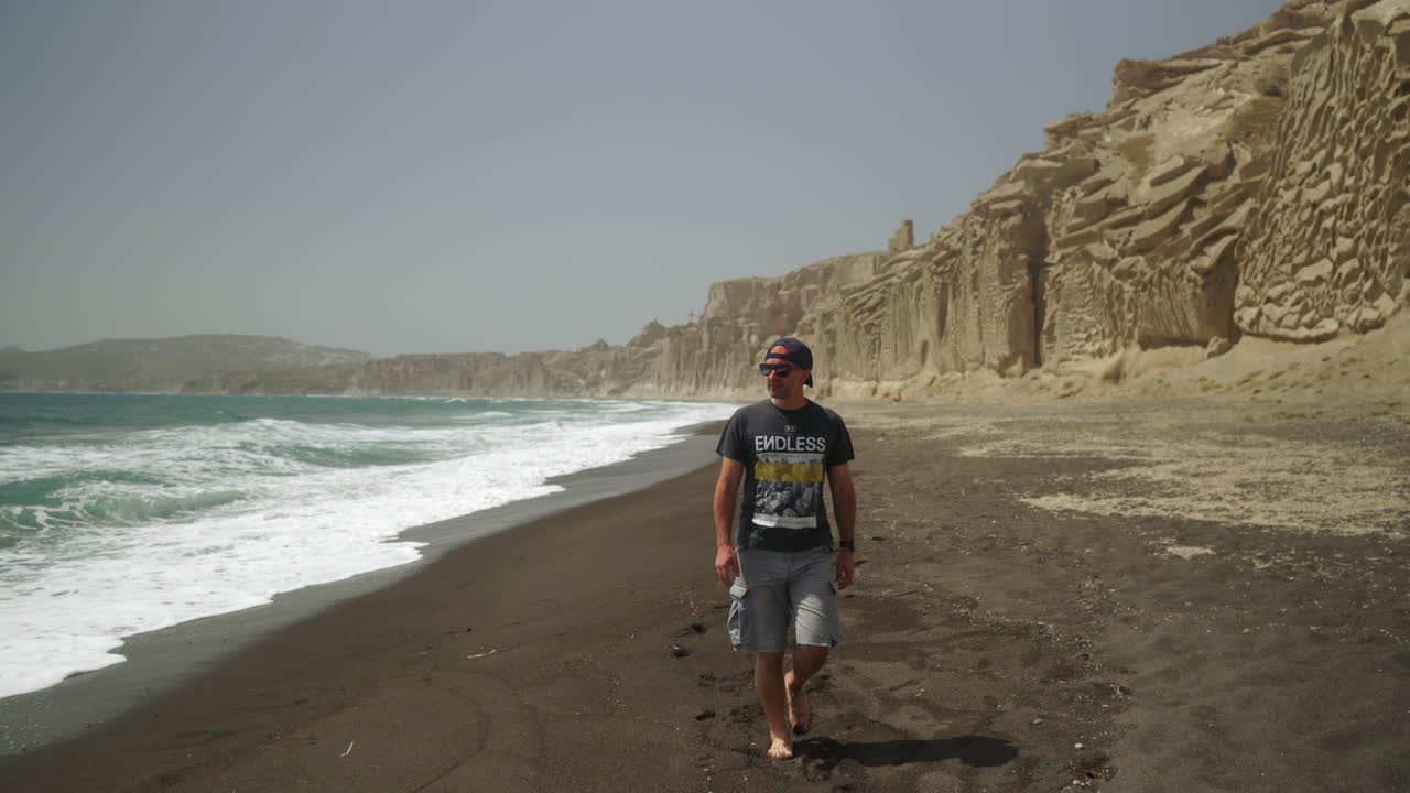 un hombre con gafas de sol camina descalzo en vlychada