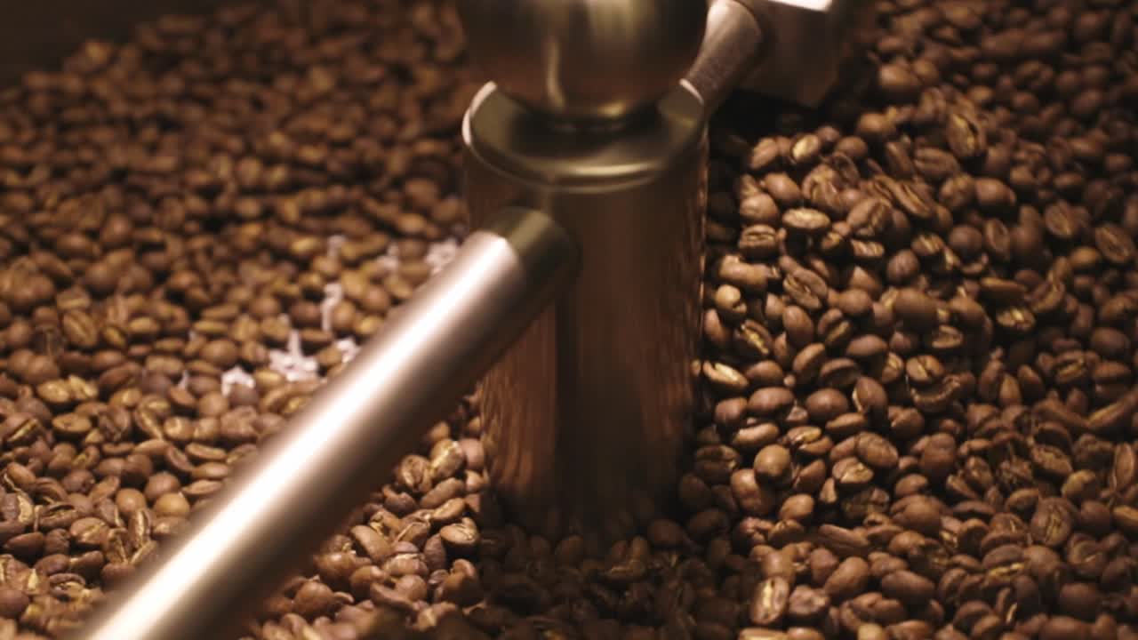 Coffee is mixed at the end of the roast, the beans are lightly roasted. Filmed close up in 50fps. You can see the individual beans tumbling.