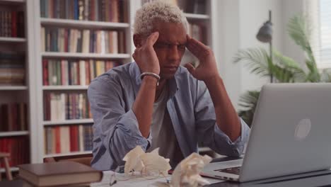 stressing african man with pain suffering from migraine rubbing his temples