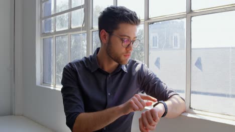 Vista-Frontal-De-Un-Joven-Hombre-De-Negocios-Caucásico-Usando-Un-Reloj-Inteligente-En-Una-Oficina-Moderna-4k