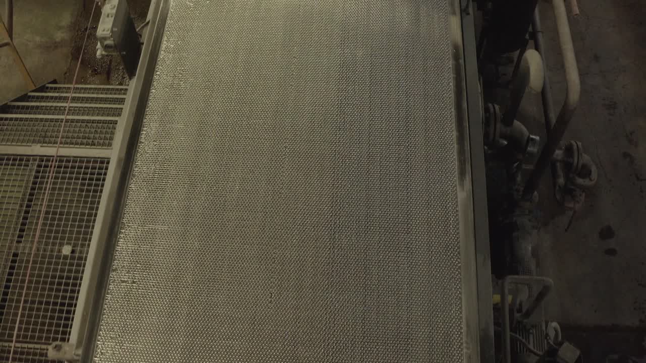 Detailed shot of textured conveyor belt or screen in motion inside industrial plant, Veille-Saint-Girons, France