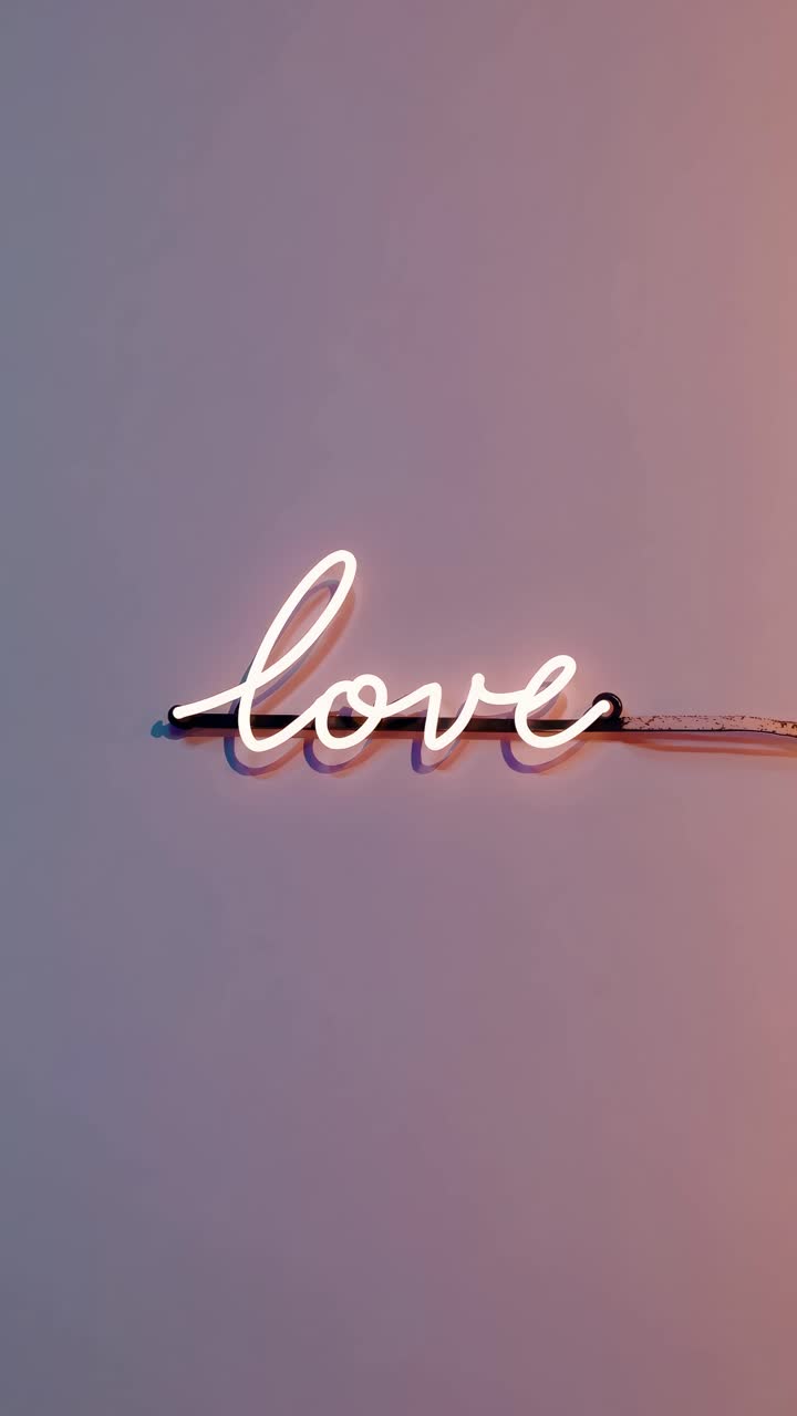 Neon 'love' sign on a pastel wall, captured from a straight-on angle