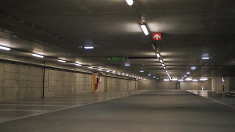 a cinematic slow motion shot capturing the quiet ambiance of an empty parking garage illuminated by overhead lights