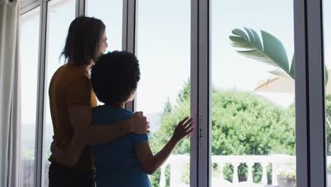 Mixed-race-couple-looking-out-of-the-window-at-home