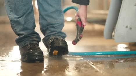 man washing boots with high-pressure water washer