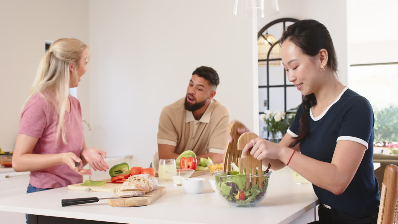 Preparing meal, young friends enjoying cooking together in modern kitchen