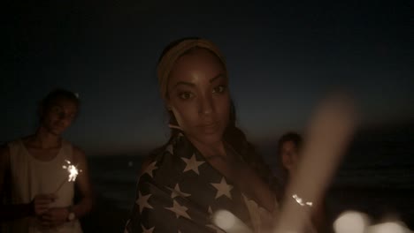 young woman and multi-ethnic friends with sparklers and american flag