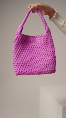 Close-Up-Vertical-Video-Of-Female-Social-Media-Influencer-Producing-User-Generated-Content-Holding-Out-Purple-Fashion-Bag-2