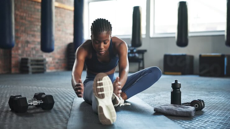 Fitness, gym and African woman stretching legs to