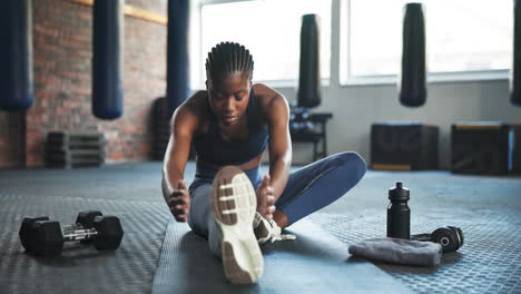 fitness, gym and african woman stretching legs to