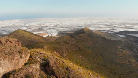 The-mountains-near-Almeria-in-the-south-of-Spain-with-in-the-background-the-greenhouses,-Aerial-shot