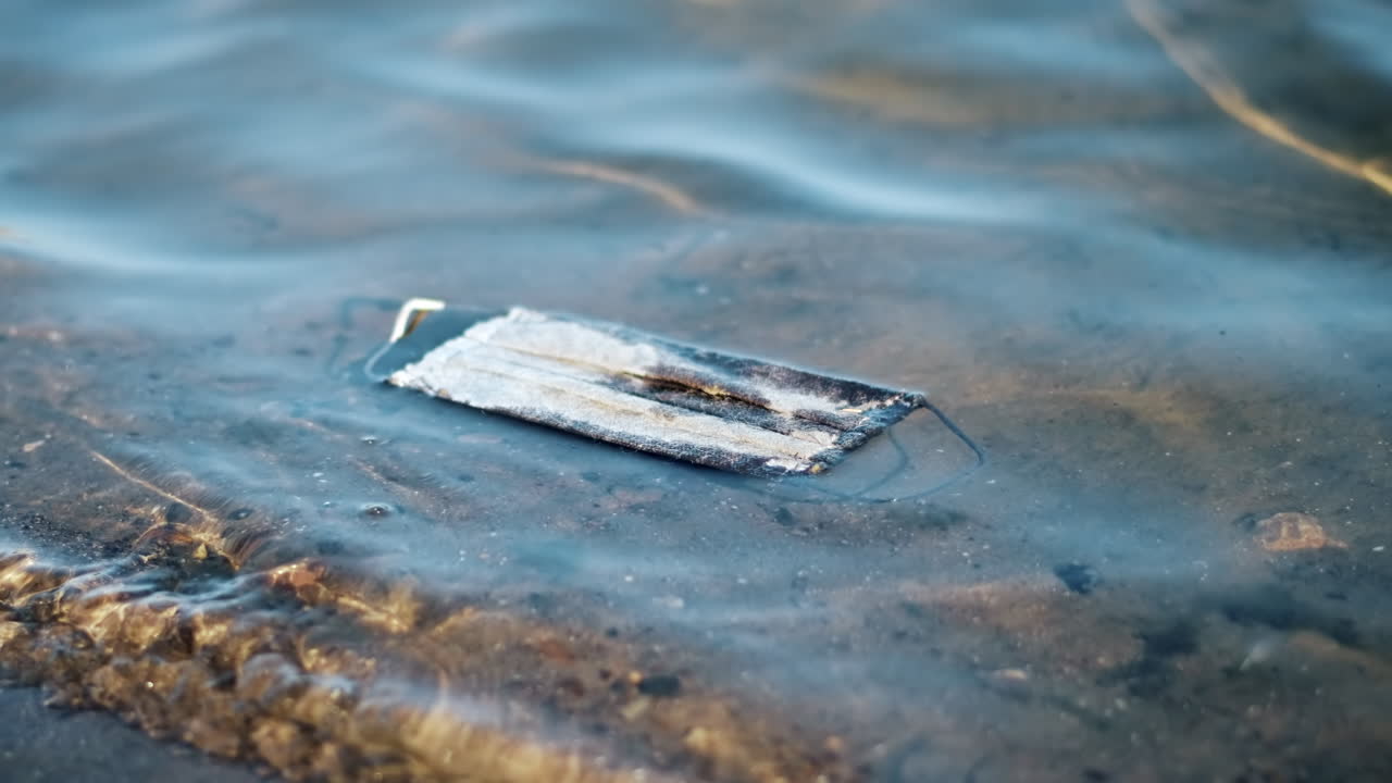 Dirty medical mask floating floating on water. Pollution idea