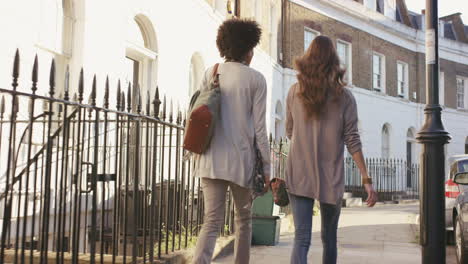 Two-beautiful-friends-walking-down-city-streets-having-fun-conversation-catching-up