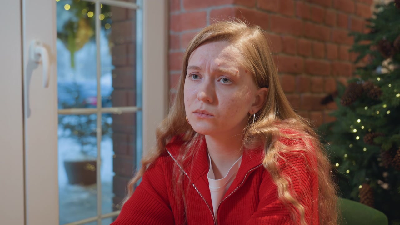 Pensive Young Woman in Red Sweater Sitting in a Cafe