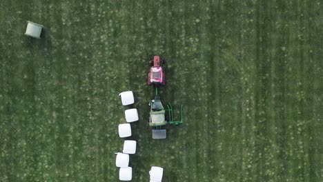 Machine-start-wrapping-fresh-green-hay-bale-to-begin-fermentation-drying,-fodder