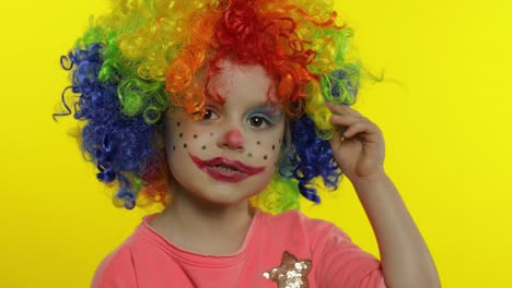 little child girl clown in colorful wig tells something interesting, having fun, smiling. halloween