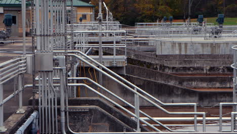 Walkways overlook a wastewater treatment aeration basin, where brown sewage water flows gently, highlighting industrial structure and controlled liquid movement