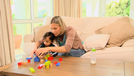 Young-mother-showing-her-baby-how-to-fit-blocks-together