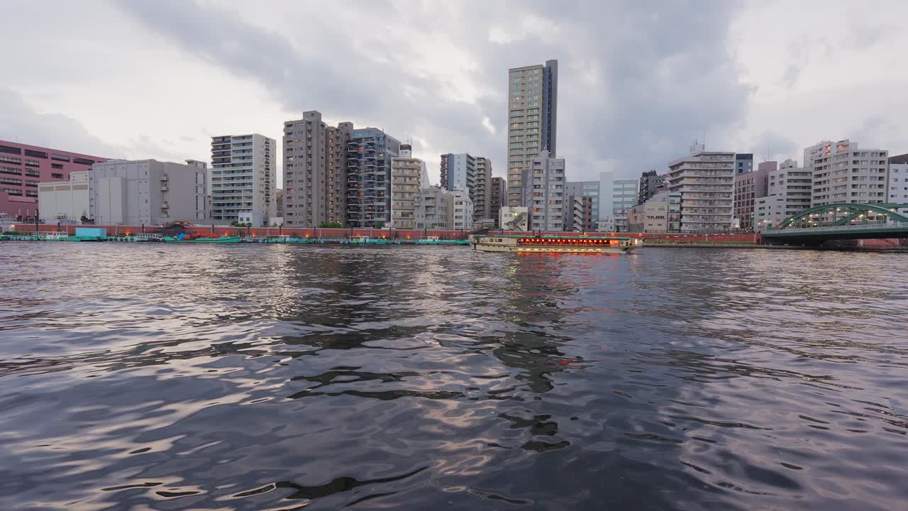 A scenic video of houseboats floating on the Sumida River at dusk, capturing the calm atmosphere of Tokyo's waterfront