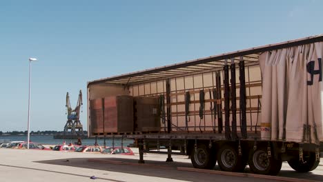 open shipping container at port with blue sky and crane nearby
