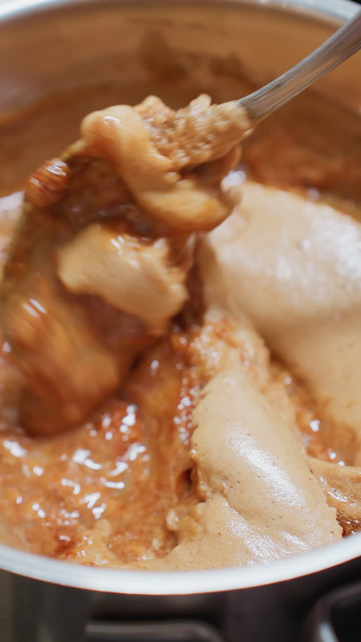 Close-up of chef stirring a pot of thick soup on an electric stove, the rich, creamy texture blends as the spoon moves, creating a smooth consistency