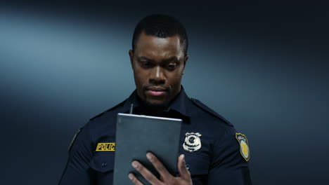 good looking policeman tapping and scrolling on the tablet device while browsing and searching information