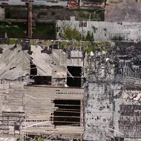 damaged roof of a building during military action. abandoned building with many holes outdoors. top aerial view. camera rising up.