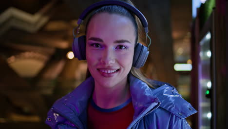 auriculares adolescentes sonriendo cámara en el metro nocturno primer plano. retrato de mujer