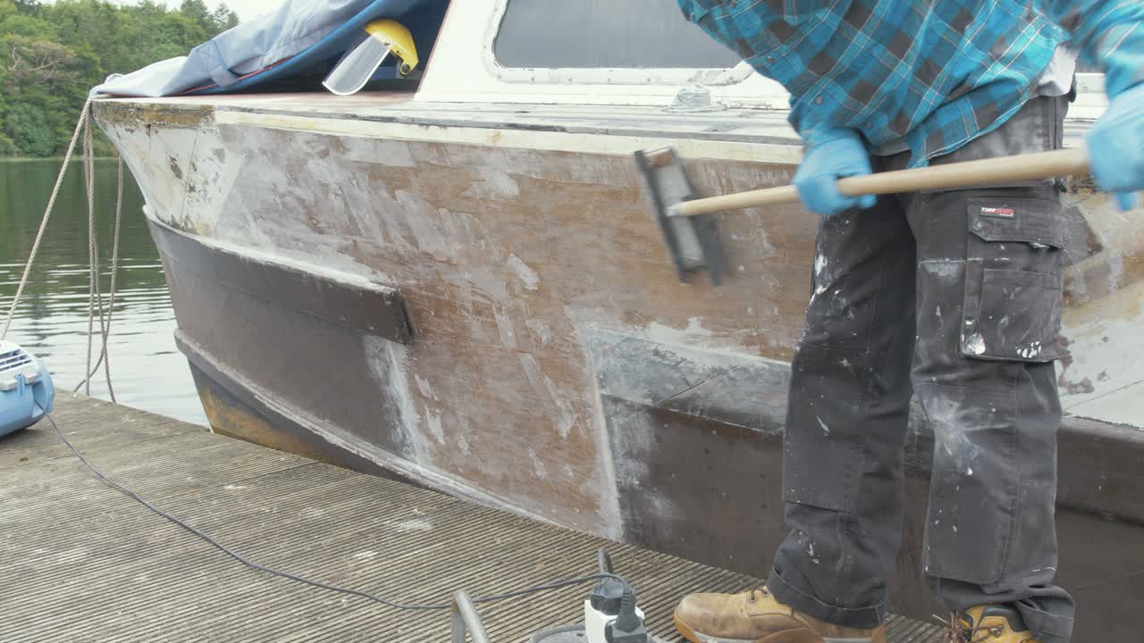 un carpintero lijando una reparación de proa de barco de madera