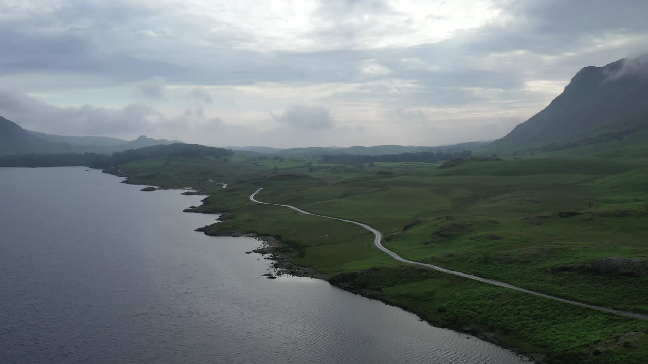 영국 호수 지구에 있는 호수 옆 산악 도로의 공중 활공 샷