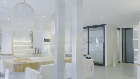 a soft panning shot of a modern spa and beauty center. the space is decorated in white, with sleek mirrors and contemporary furniture.