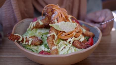 woman eating a caesar salad with crispy fried chicken