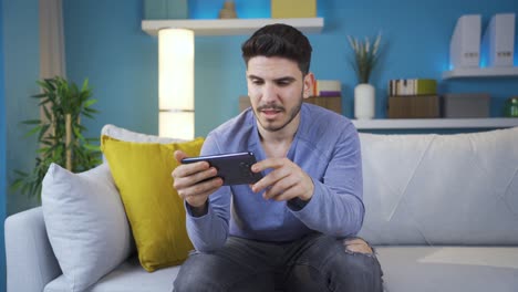 young man watching emotional movie on smartphone alone at home.