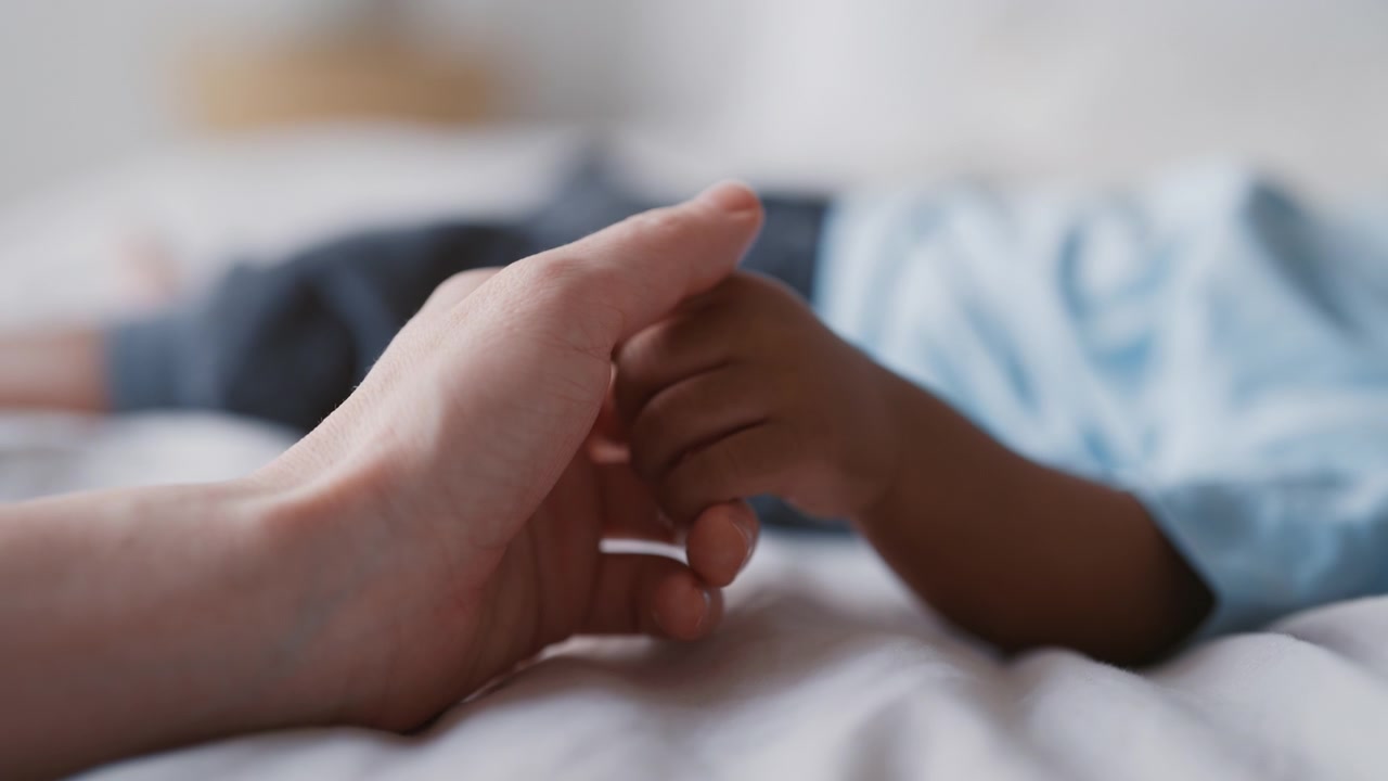 Parent Holding Hand of Sleeping Child in Bed