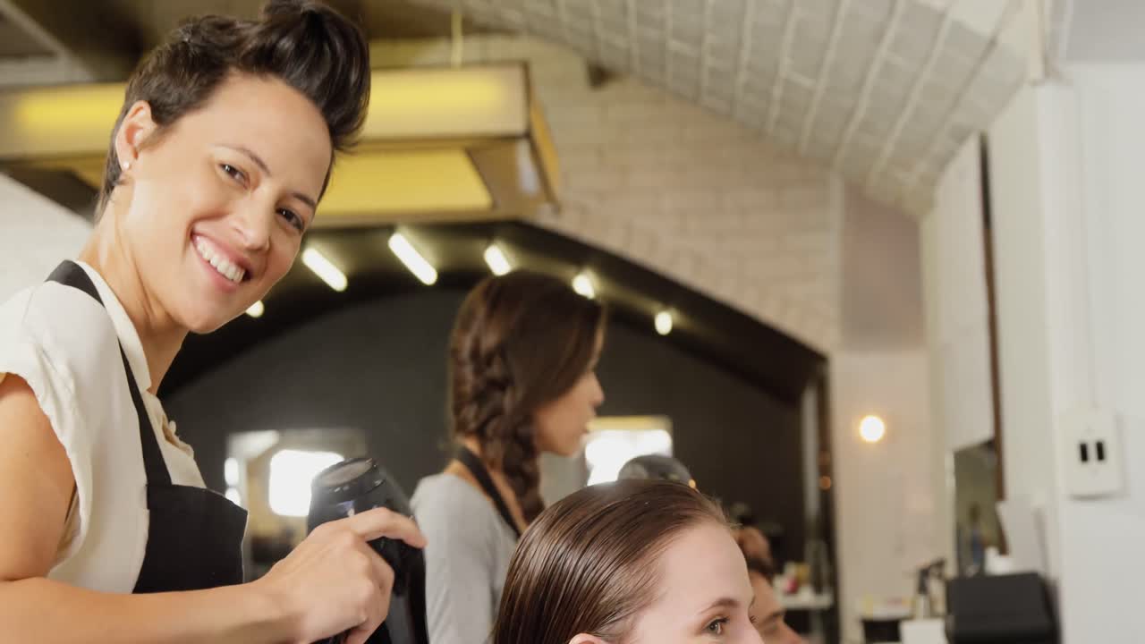 Female hairdresser blow drying her client hair