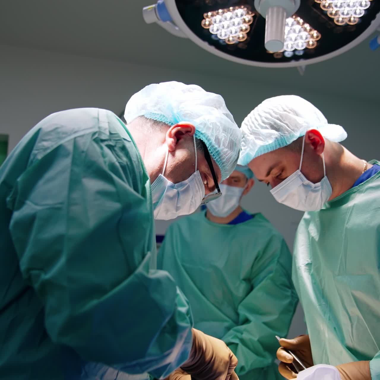 Chirurghi professionisti che utilizzano strumenti nel loro lavoro in sala operatoria. Vista laterale dei medici che eseguono un'operazione.